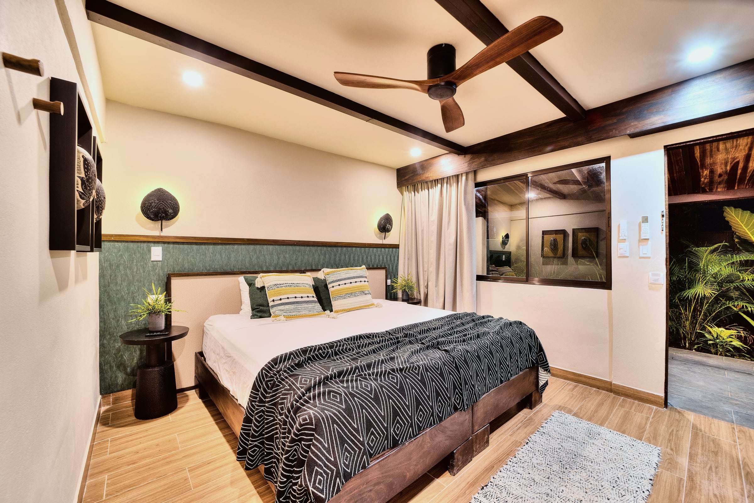 Deluxe Garden King at night: king bed, green headboard wall, woven sconces and a door open to a lit garden patio