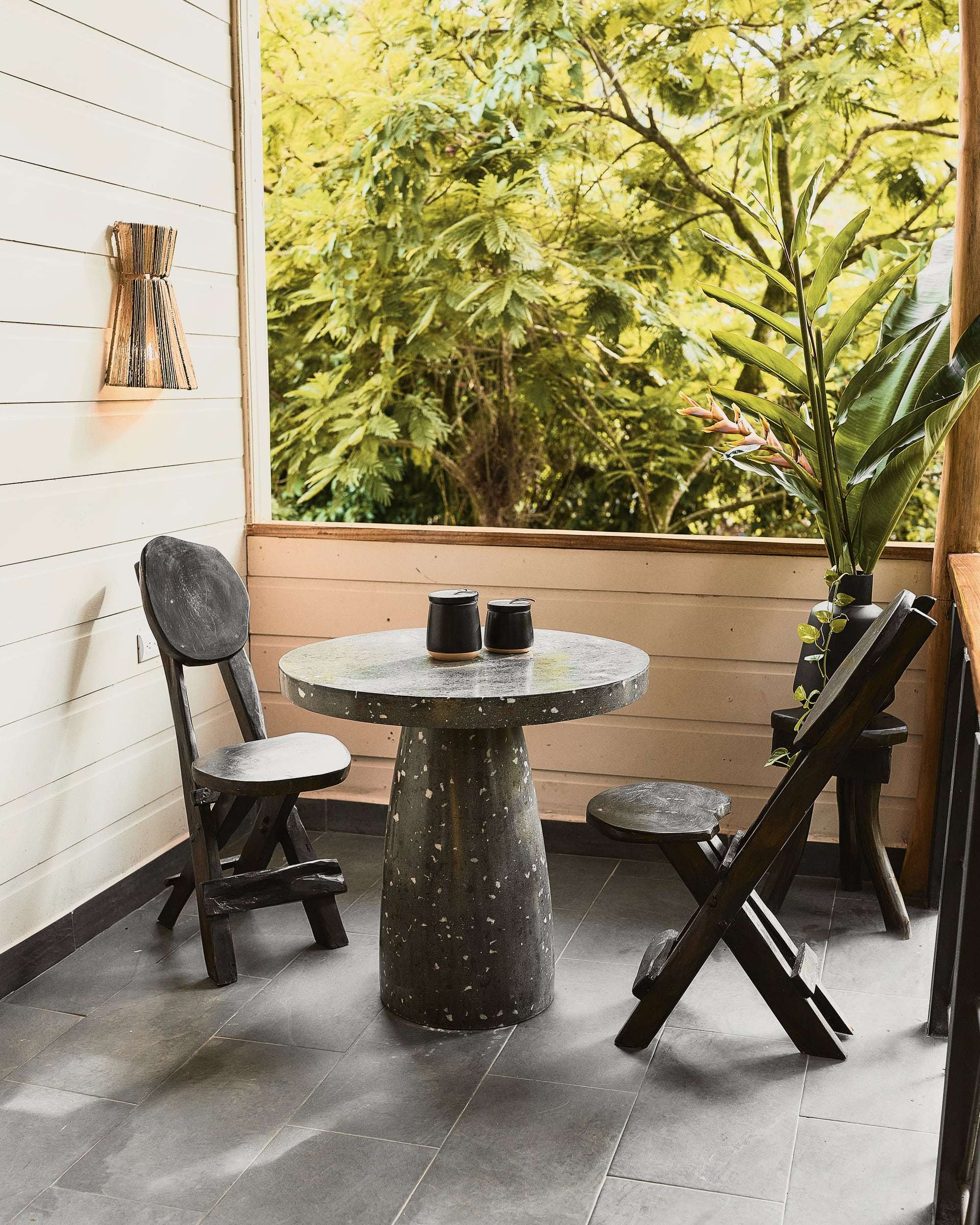 Private terrace with a terrazzo table for two, carved wooden chairs and a view into the treetops