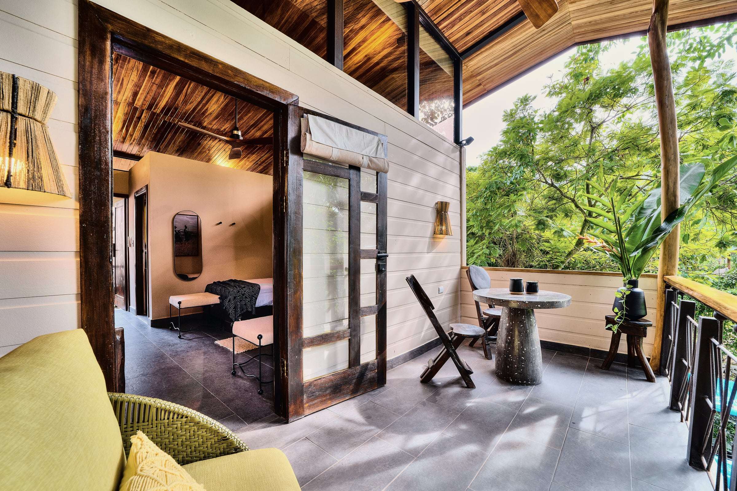 Suite terrace with a yellow armchair and terrazzo table, looking back through the door into the bedroom