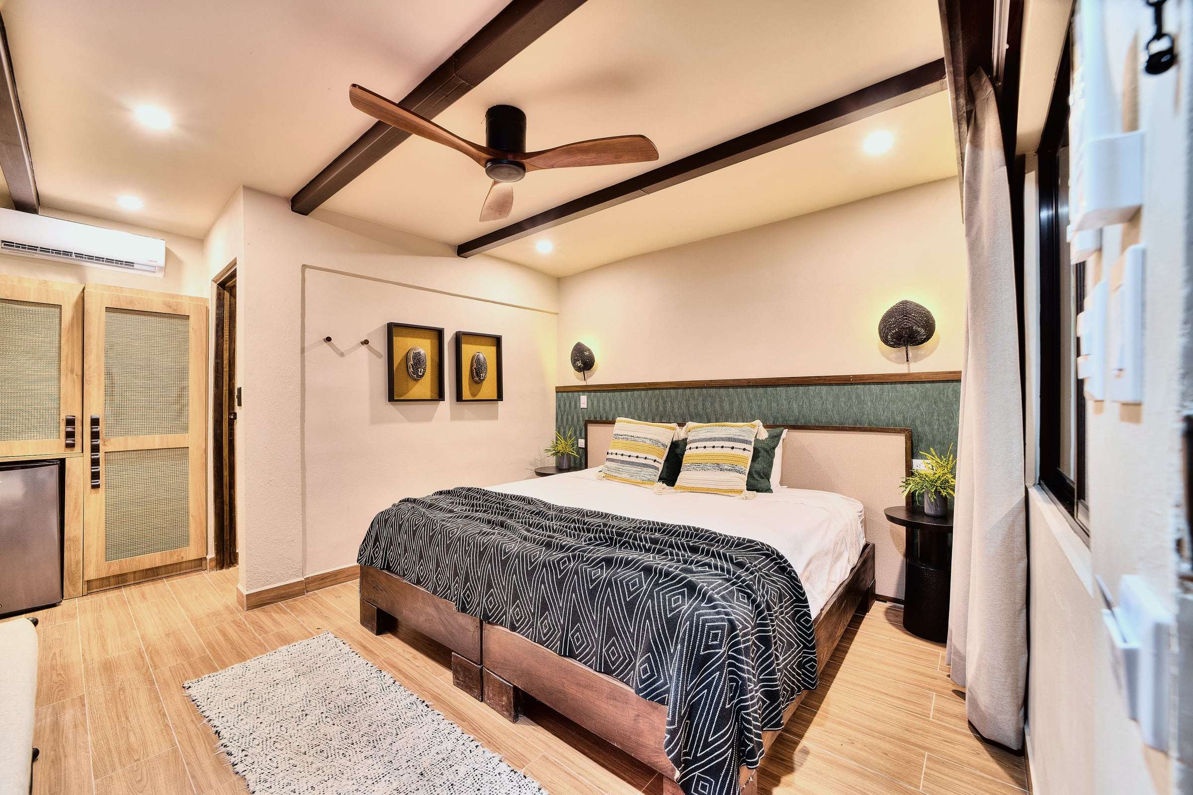Deluxe Garden King: king bed with a geometric throw, green headboard wall, woven sconces and a wardrobe with minifridge