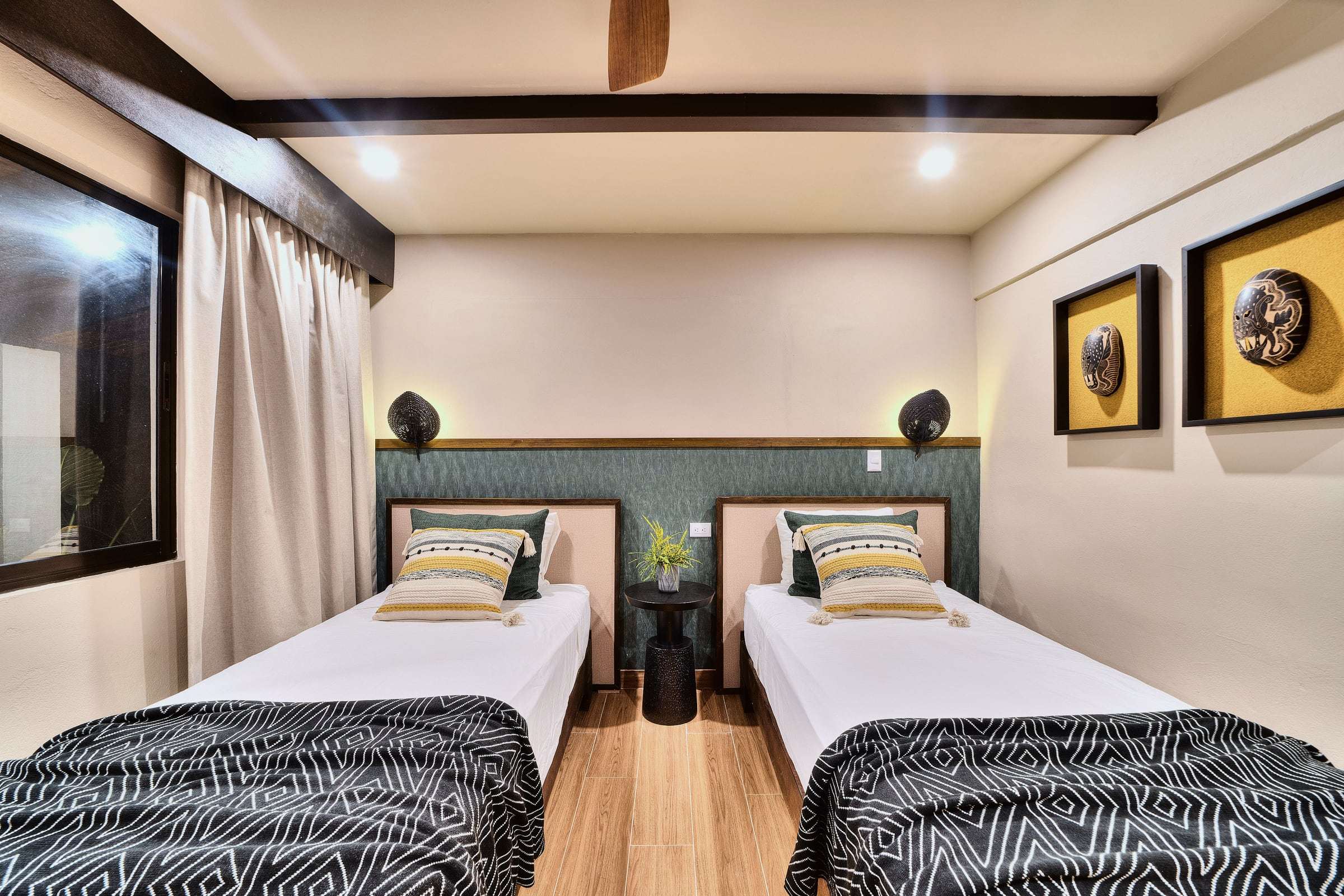 Superior Garden Room with twin beds, black-and-white throws, a green headboard wall and framed hand-carved masks