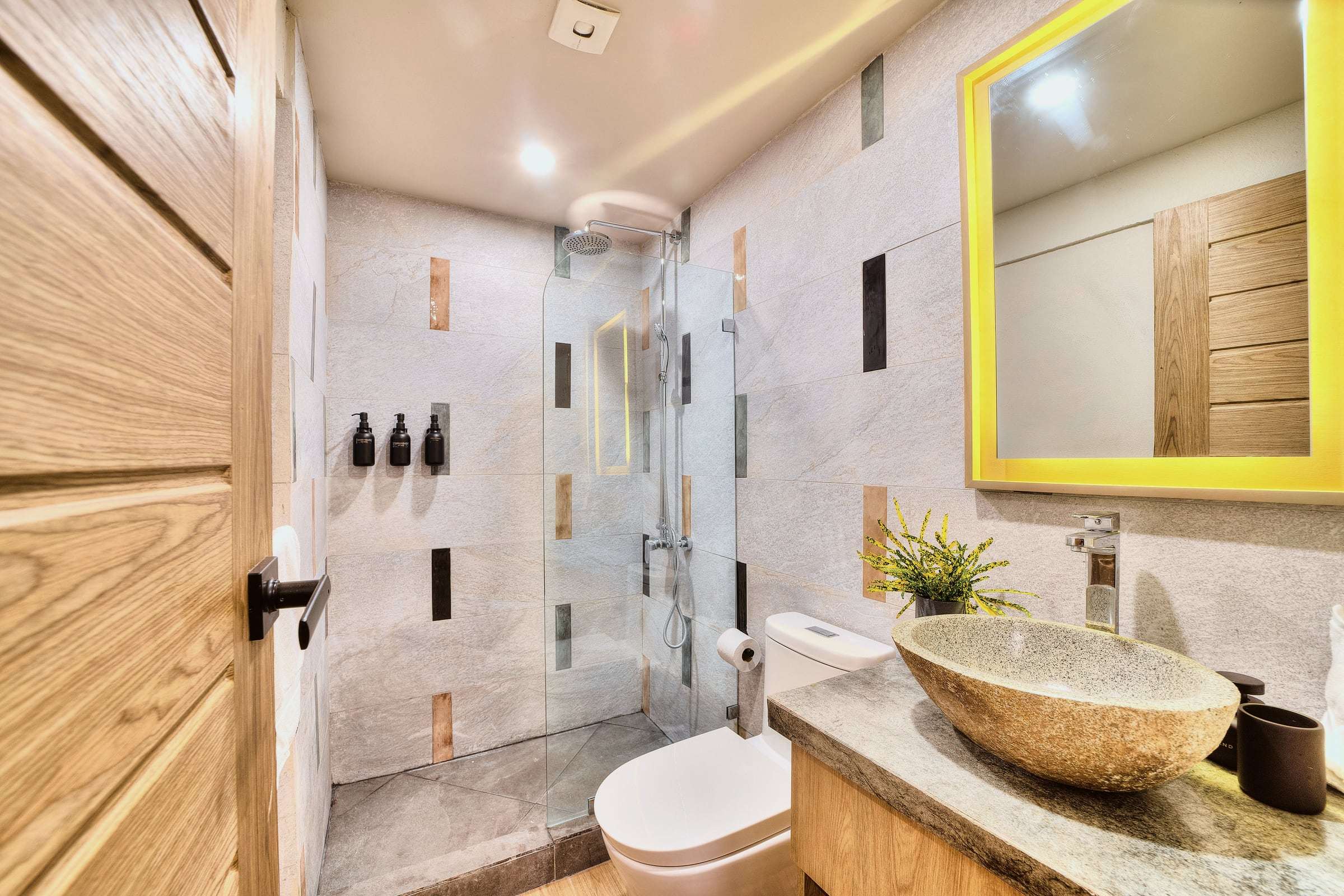 Superior Garden Room bathroom: river-stone vessel sink, backlit mirror and a glass-screened rain shower in stone tiles