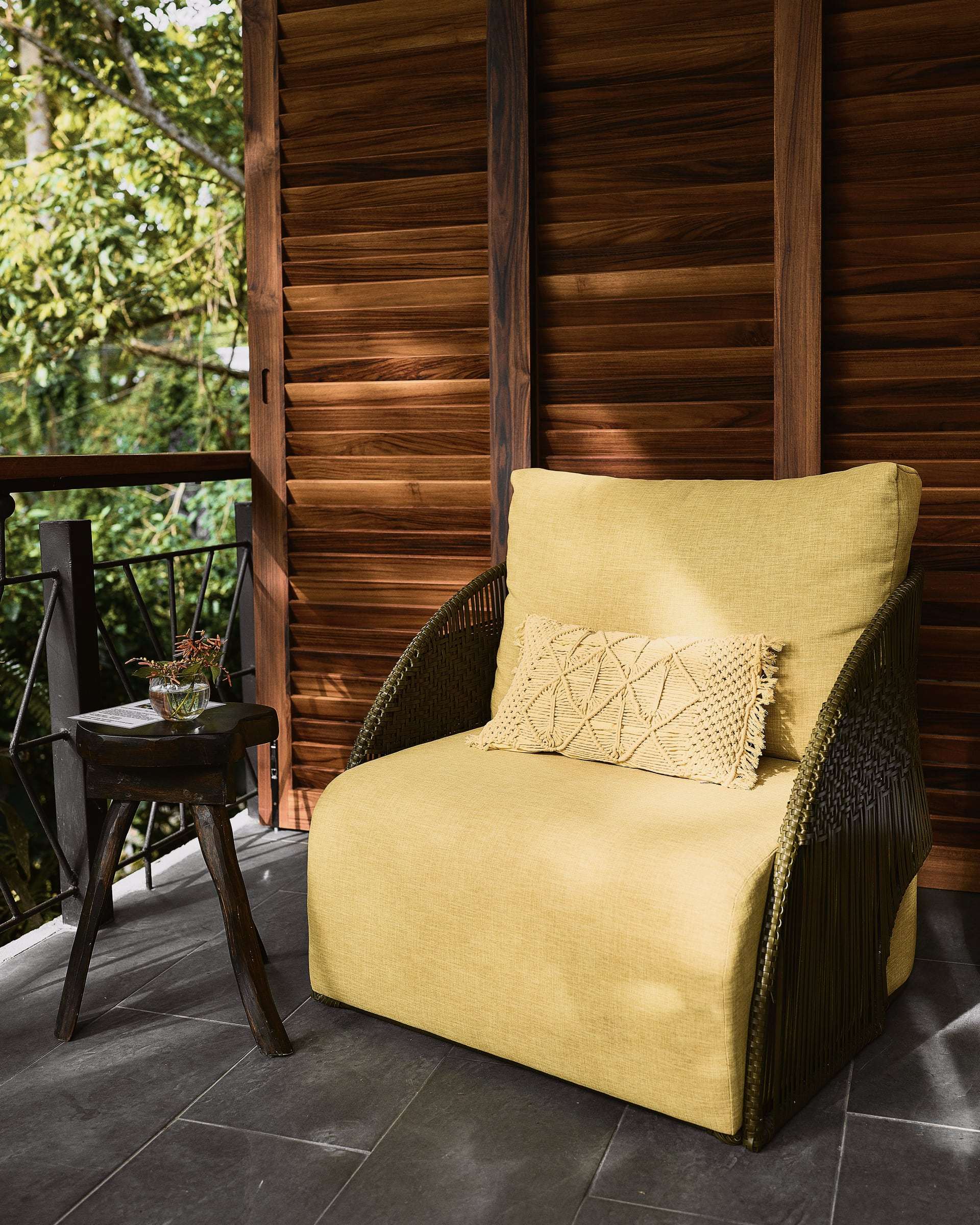 Terrace Suite: yellow cushioned armchair with a macramé pillow beside wooden louvred shutters on the terrace