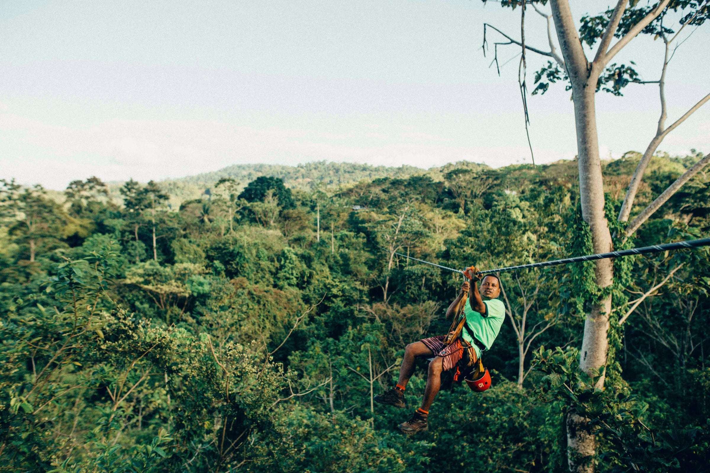 Rider in a harness gliding along a zipline cable above the forest canopy in Costa Rica