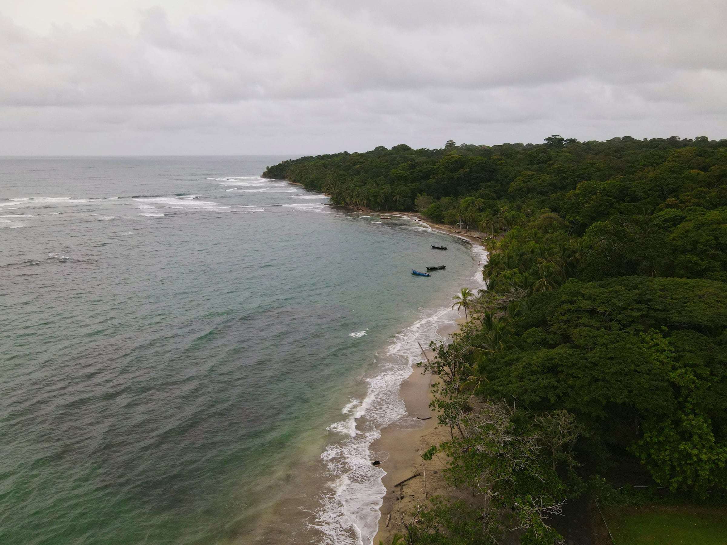 Aerial view of small boats moored off a jungle-backed beach on the Caribbean coast of Limón, Costa Rica