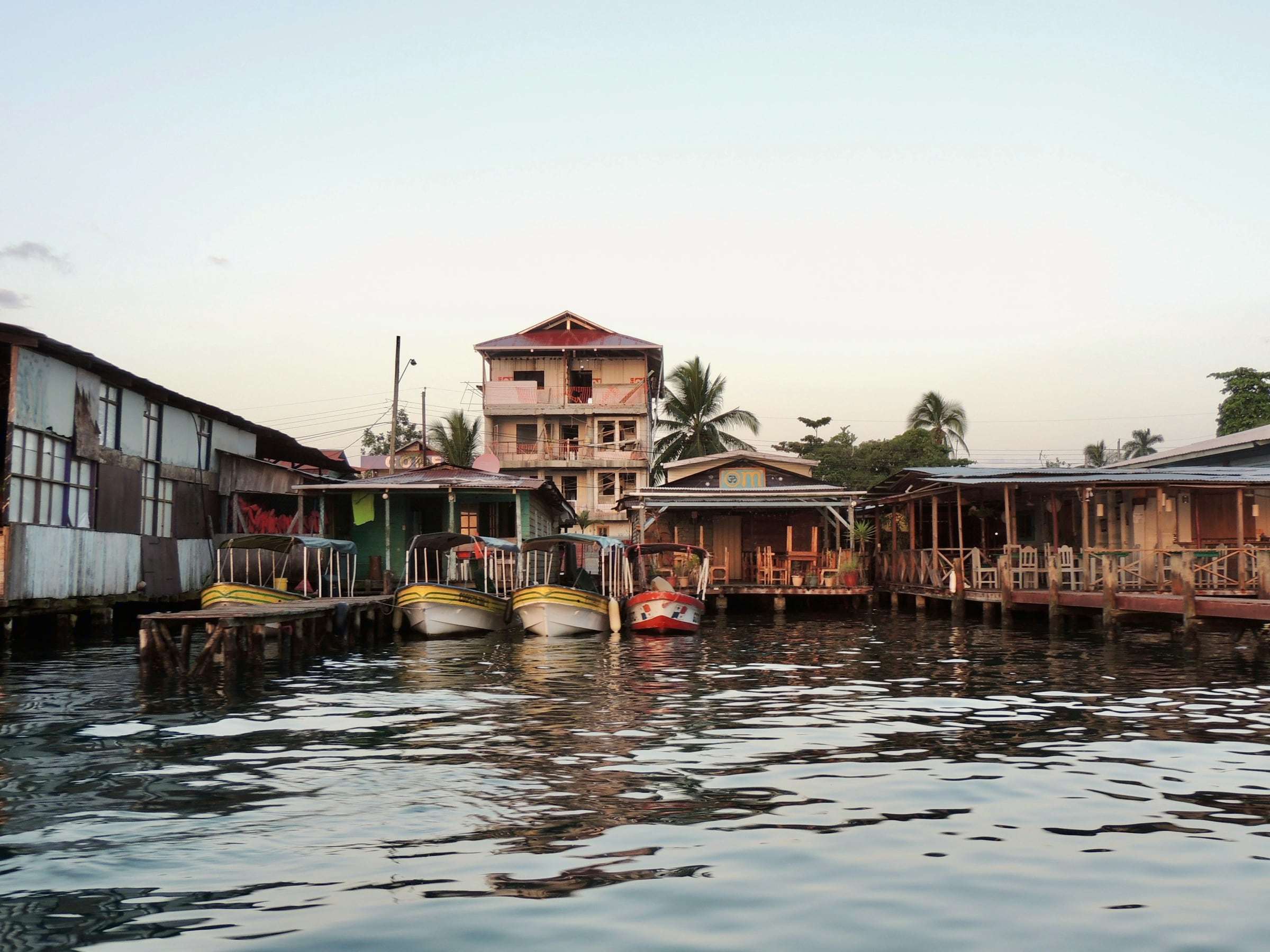Wooden buildings on stilts and moored water taxis along the waterfront of Bocas del Toro, Panama, at dawn